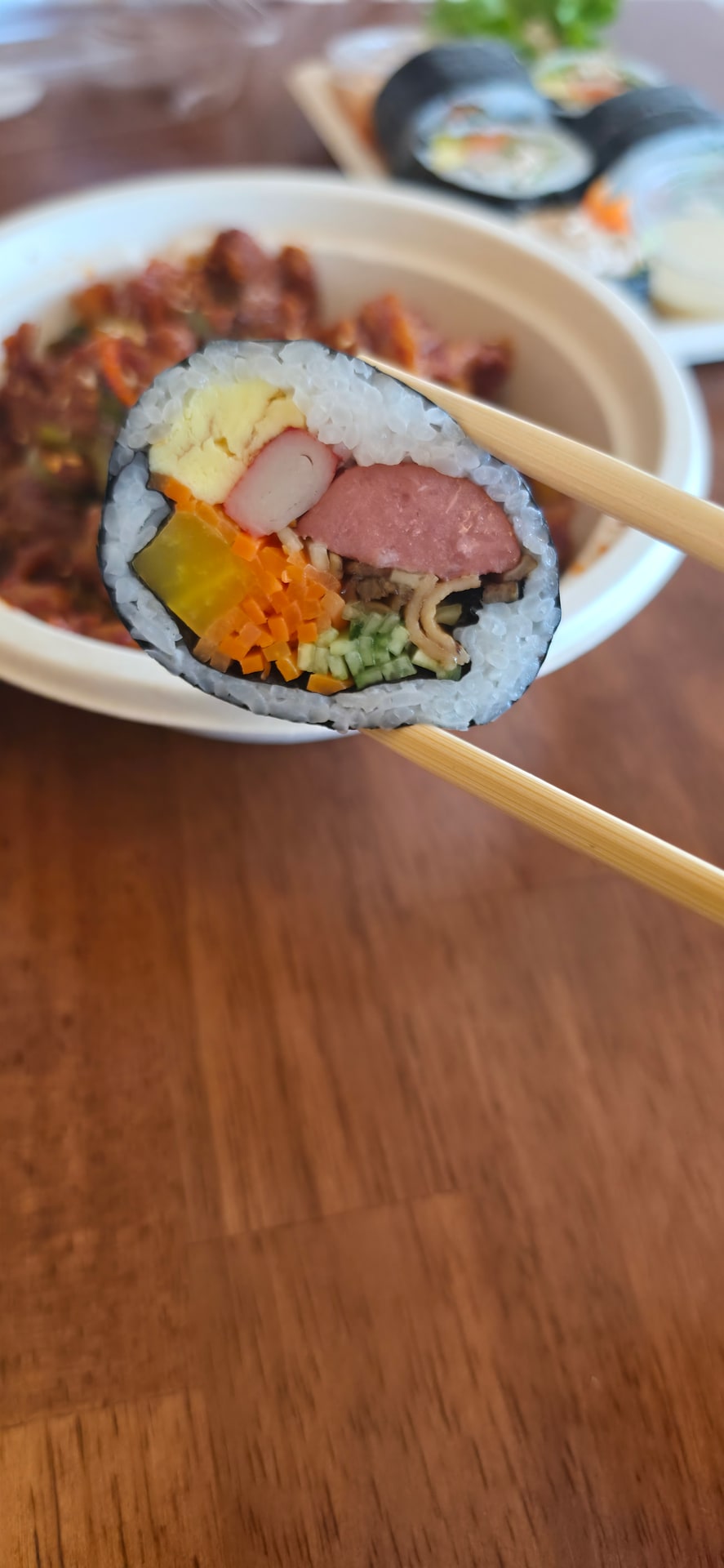 젓가락으로 집어 든 오리지널 김밥의 단면